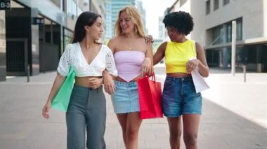 Alışveriş çılgınlığından sonra şehirde birlikte yürüyen üç genç bayan arkadaş.