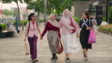 Tesettürlü Asyalı kadınlar ve açık havada eğlenmek - Mutlu Endonezyalı bayan arkadaşlar alışveriş yaparken geziniyor ve konuşuyorlar