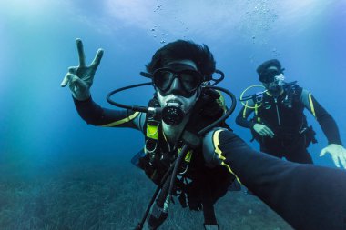 İki arkadaş tüplü dalış yapıyor, selfie çekiyor, okyanusun derinliklerinde tatilin tadını çıkarıyor.