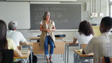 Kolej öğrencileri, lisede motivasyon bilimi dersi veren tutkulu bayan profesörü dinliyorlar.