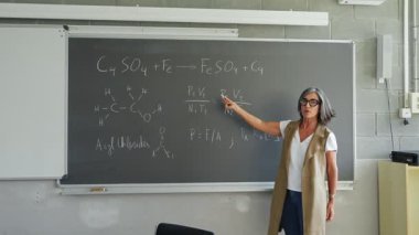 Bayan profesör, kimya dersini lisede Teknoloji Bilimi dersi alan üniversite öğrencilerine anlatıyor.