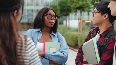 Afrika kökenli Amerikalı kız öğrenci ve grup arkadaşları üniversite binasının önünde toplanıp okul projesi hakkında konuşuyorlar. 