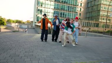Young woman with group of friends dancing in the city with energy and trendy attitude