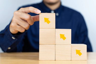 Businessman putting wooden cube with arrows pointing up. Concept of business success growth increase up