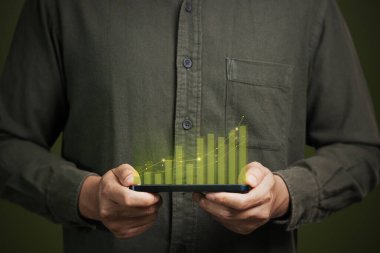 Büyümenin ve başarının sembolü olarak cep telefonunu elinde tutan bir adam ya da gelecekte başarılı gelişmeler ve iş geliştirme çabaları gösteren bir adam. İş ekonomisi ve teknoloji kavramı