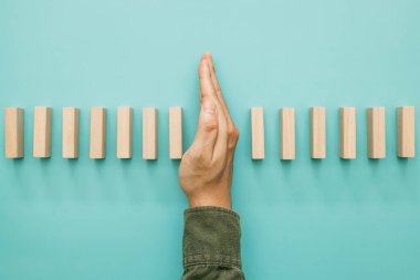 İş risk yönetimi konsepti. İşadamı, tahta masa üzerindeki domino etkisini durduruyor. İş stratejisi