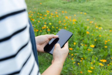 Yakın plan el ele tutuşmalar, arka planda akıllı telefonlar. Şehir parkında cep telefonu kullanan kadın.