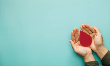 Bağış kavramı, kan bağışı, kan nakli, dünya hemofili, dünya AIDS ve HIV günü. Kan vermek için elinde bir damla kan tutuyordu. en üstteki görünüm