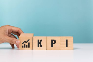 KPI, Personel Yasaklama, Temel Performans Göstergesi konsepti. KPI kısaltmalı tahta küpler ve grafik başarının değerlendirmesini gösteriyor