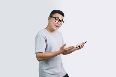 Şaşırmış mutlu adamın portresi kameraya bakıyor. Akıllı telefonu tutarken yüz ifadesini gösteriyor.