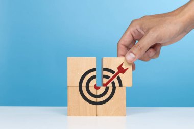 İş başarısı, başarılı hedefler. Hedef simgesine tahta bloklar koyan bir adam ki bu da başarılı olan hedefleri gösteren son parçadır.