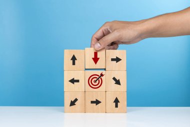 Hedefe doğru kasıtlı hareket kavramı. Elle tutulan kırmızı oklu tahta küp başarılı bir hedef için hedefe doğru ilerliyor
