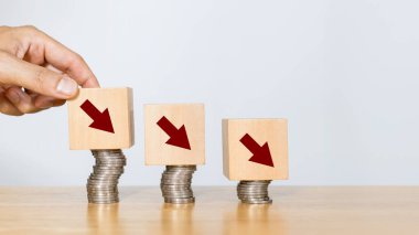 Maliyet, ekonomik durgunluk ve maliyet azaltma kavramı. Elle tahta bloğu aşağı ok işareti ile koymak ekonomik durgunluğu veya karı maksimum seviyeye çıkarmak için yapılan harcamaları gösteriyor