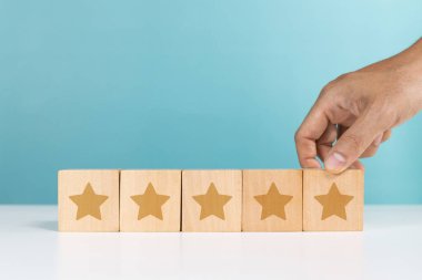 Service rating, positive feedback, satisfaction concept. A man holding wooden cube with star icon give five star rating indicating satisfaction level of service users clipart