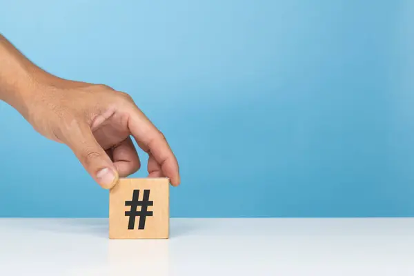 Etiket sembolü, moda, gönderme ve etiketleme. Masaya hashtag sembollü tahta blok koyan bir adam.