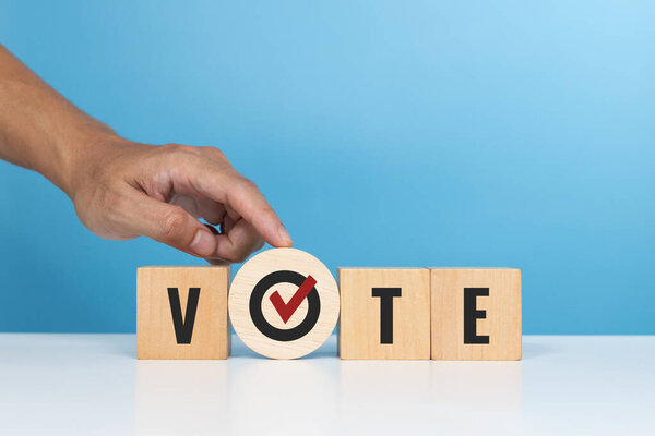 VE, выборы, опросы и голосовые знаки. Деревянные кубики со словом "Голосуйте" с галочкой на столе в офисе