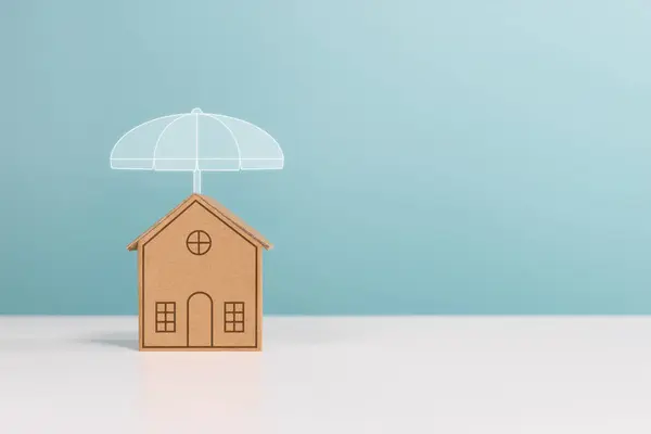 stock image Protect property, mortgage, home, investment and financial savings concept. Miniature house under the umbrella with copy space on green background