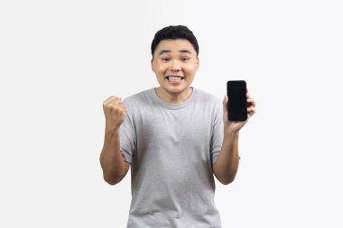 Heyecanlı adam portresi kamera ve eli bir yumruğa yapışmış ve diğer el beyaz arka planda izole akıllı telefonu tutuyor.