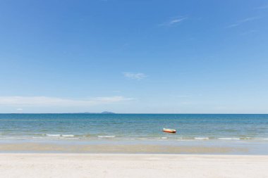 Sahildeki deniz alanı. Güzel tropikal plaj ve mavi gökyüzü ve güneşli bir günde beyaz bulutları olan şişme tekne.