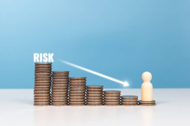 Yatırım riski, risk analizi, iş kararı. Tahta heykelcikler ayakta duruyor ve paralar aşağı ok ile istifleniyor. Bu da iş ve yatırım risklerini gösteriyor.