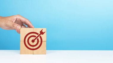 Hedef, iş başarısı, başarılı hedefler. Hedef simgesine tahta bloklar koyan bir adam ki bu da başarılı olan hedefleri gösteren son parçadır.