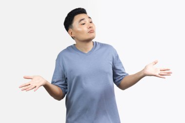 Asyalı mutlu gülümseme portresi beyaz arka planda izole edilmiş mavi bir tişört giyiyor. Erkekler el kaldırır, alay eder, alay eder.