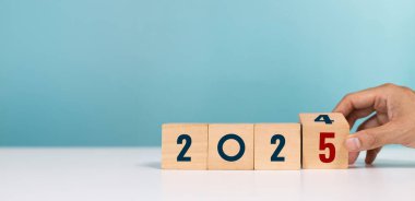 Mutlu yıllar 2025. 2025 gol planlaması. Ofisteyken 2024 'ten 2025' e kadar el değiştiren tahta küpler.