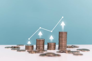 Yatırım, faiz oranları, kar payı, mevduat, iş, finans ve yatırım. Artan madeni para yığınlarıyla yukarı oklar mavi arka planda yatırım artışını gösteriyor