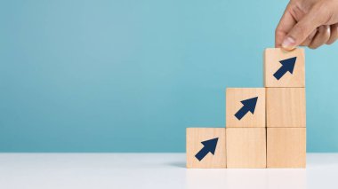 Tahta blokları basamakları ok ile merdiven olarak yerleştiren bir adam, iş büyüme sürecini işaret ediyor