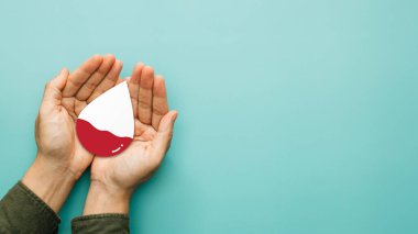 Kan bağışı, bağış, kan nakli, dünya hemofili ve AIDS ve HIV günü konsepti. Kan vermek için elinde bir damla kan tutuyordu. en üstteki görünüm