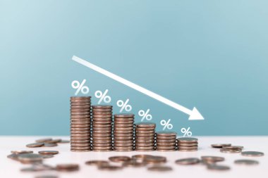 Yüzdelik işaretler ve aşağı doğru bir ok ile kademeli olarak boy olarak azalan bozuk para yığını, azalan faiz oranları, yatırım geri dönüşleri veya ekonomik daralmayı sembolize eder