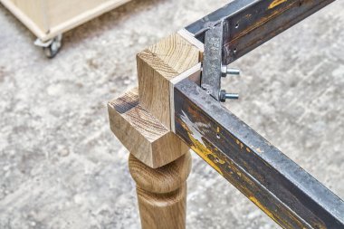 Som meşe ağacından ahşap oyma bacak ve metal masa çerçevesi atölyede yemek masası imalatı sırasında yakın görüş.