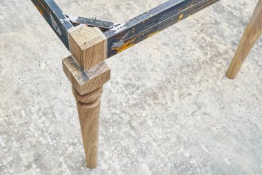 Som meşe ağacından ahşap oyma bacak ve metal masa çerçevesi atölyede yemek masası imalatı sırasında yakın görüş.