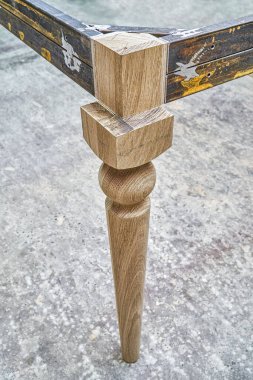 Som meşe ağacından ahşap oyma bacak ve metal masa çerçevesi atölyede yemek masası imalatı sırasında yakın görüş.