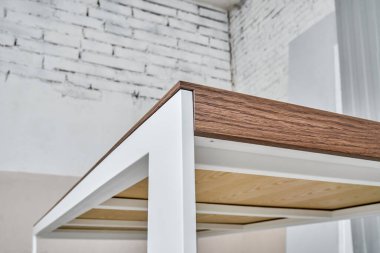 Minimalizm stili yemek masası, ince ahşap masa, meşe kaplaması, beyaz metal bacaklar, atölyede yakın çekim, alçak açı.