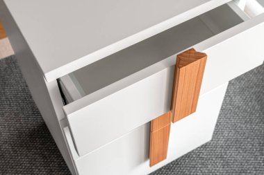 Stylish white office commode with wooden handles and legs with open empty drawers closeup view. Comfortable furniture for home and office furnishing clipart