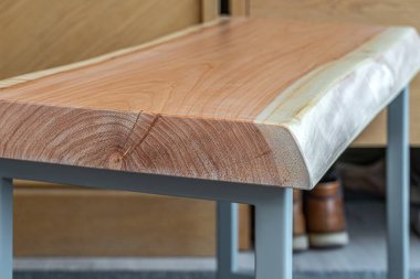 Canlı ahşap kaplamalı bank ve modern tasarımda gri metal bacaklar oturma odasında, pencerenin yanında halı kaplı zemin ile.