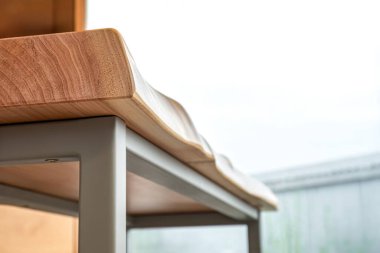 Canlı ahşap kaplamalı bank ve modern tasarımda gri metal bacaklar oturma odasında, pencerenin yanında halı kaplı zemin ile.