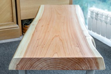 Canlı ahşap kaplamalı bank ve modern tasarımda gri metal bacaklar oturma odasında, pencerenin yanında halı kaplı zemin ile.