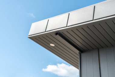 Ayakta dikilen dikiş yüzüyle modern misafir evi ve parkın çatısında asılı duran geniş bir çatı. Minimalist mimari tarzı yakın plan