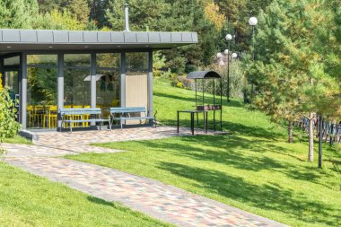 Yazlık otelin bahçesinde cam duvarları ve barbekü alanı olan bir misafir evi. Bahçesinde ızgara ekipmanı olan bir kafe. Dinlenecek yer