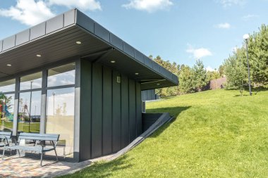Ayakta dikilen panoramik cilalı ve parktaki büyük düz çatılı modern misafir evi. Kamu binasının minimalist mimari tarzı
