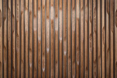 Dekoratif ahşap panel dikey oluklu levhalardan yapılmış, çeşitli kenar desenleri var, arka plan olarak desenli bir yüzey yaratıyor.