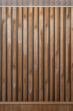 Dekoratif ahşap panel dikey oluklu levhalardan yapılmış, çeşitli kenar desenleri var, arka plan olarak desenli bir yüzey yaratıyor.