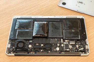 Kırık dizüstü bilgisayarın şişmiş bataryası, açık kaplamayla kapatılmış. Onarım servisinde dizüstü bilgisayarın ağır hasar görmesi. pc ile problem
