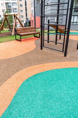 Canlı lastik döşemeleri, bankları ve tırmanma ekipmanlarıyla dolu oyun alanı binalarla çevrili, açık hava aktivitesini destekliyor.
