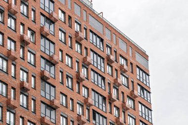 Kırmızı tuğlalı, cam cepheli, balkon ve pencereli çağdaş çok katlı binalar. Kentsel mimari konsepti, düşük açı görünümü