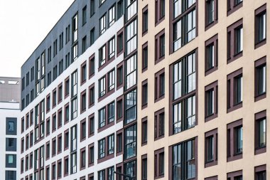 Çelişkili renkleri ve geniş koyu çerçeveli pencereleri olan modern çok katlı bir apartman. Kentsel konut kavramı