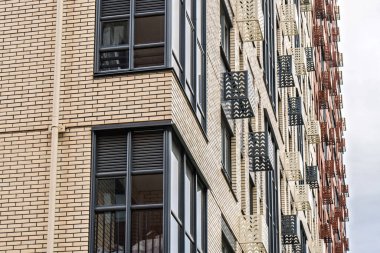 Çağdaş çok katlı binalar, bej, kırmızı tuğla ve cam cepheleri, koyu çerçeveli balkonları ve pencereleri, düşük açılı manzaralı.