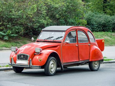 Prag, Çek Cumhuriyeti - 31 Ağustos 2007: Klasik kırmızı retro otomobil Citroen 2CV6 şehir caddesinde park halindeki yeşil yeşillik arka planda klasik ulaşım kavramı